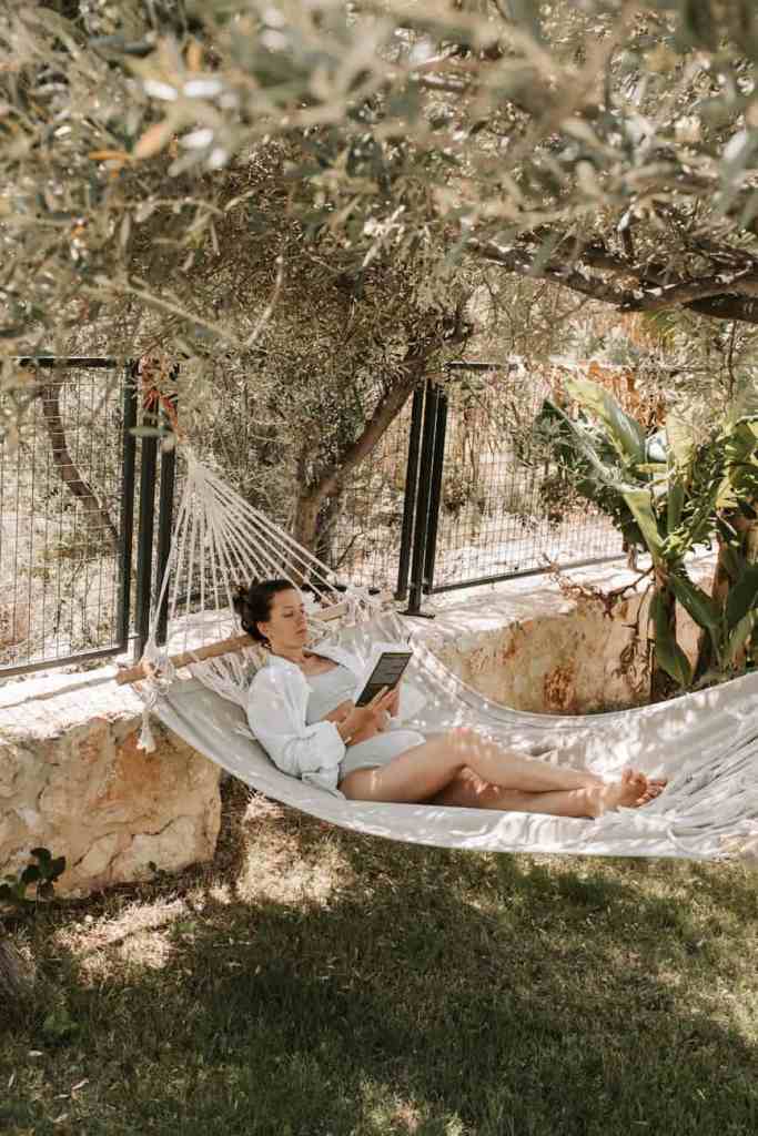 woman reading a book while lying on a hammock